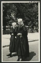 2 vues  - [Femmes en costume traditionnel près des halles.] / Godineau. Photographe. 1940-1950 (ouvre la visionneuse)